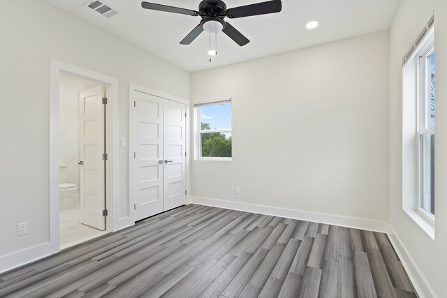 unfurnished bedroom featuring ceiling fan, a closet, hardwood / wood-style floors, and connected bathroom