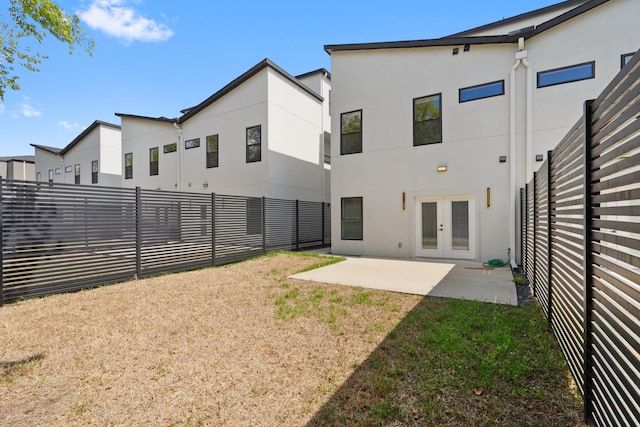 back of property with french doors, a lawn, and a patio area