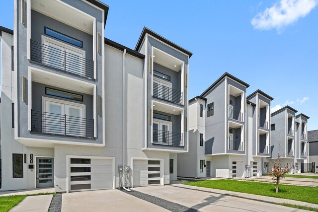 view of front facade featuring a garage, a balcony, and a front lawn