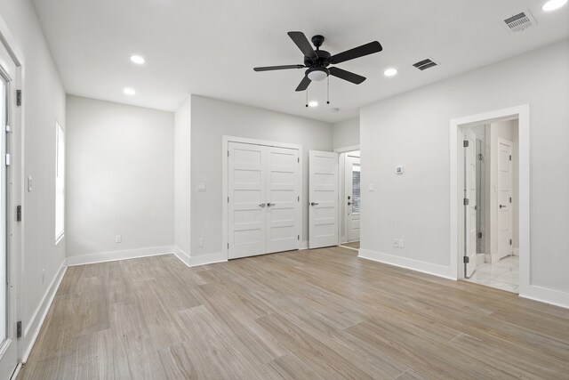 unfurnished bedroom featuring ensuite bathroom, ceiling fan, and light hardwood / wood-style flooring