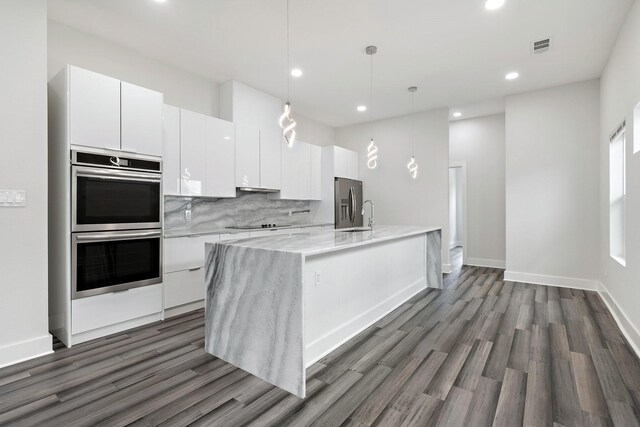 2507 Crossman Ave, Dallas, TX 75212 - kitchen with stainless steel appliances, modern cabinets, white cabinets, dark wood-style floors, and a center island with sink