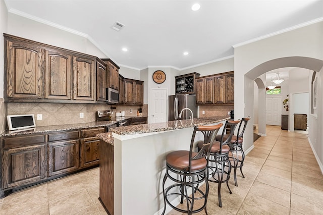 kitchen with a kitchen island with sink, light stone countertops, and appliances with stainless steel finishes