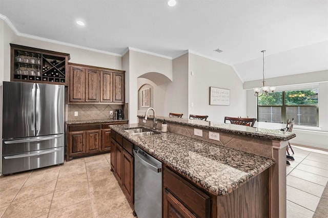 kitchen featuring sink, a notable chandelier, dark stone countertops, an island with sink, and appliances with stainless steel finishes