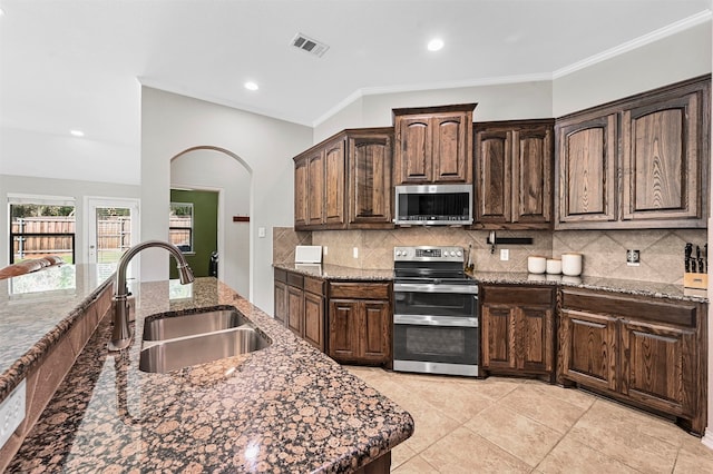 kitchen featuring appliances with stainless steel finishes, ornamental molding, dark stone countertops, and sink