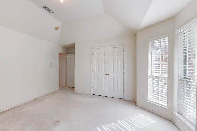 unfurnished bedroom with light carpet, a closet, and vaulted ceiling