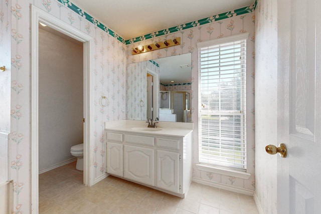 bathroom featuring tile patterned flooring, vanity, a shower with door, and toilet