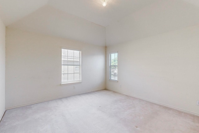 carpeted spare room with vaulted ceiling