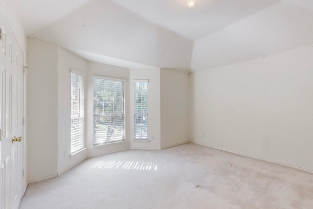 spare room with light carpet and vaulted ceiling