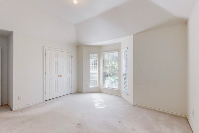 empty room with light carpet and vaulted ceiling