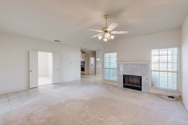 unfurnished living room featuring light tile patterned flooring, a high end fireplace, and ceiling fan