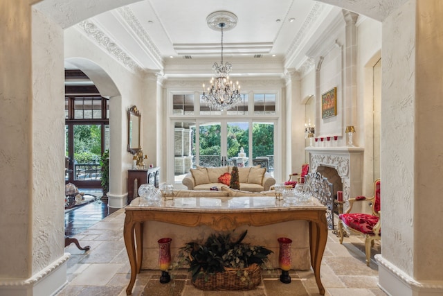 living area with a raised ceiling, ornamental molding, and a chandelier