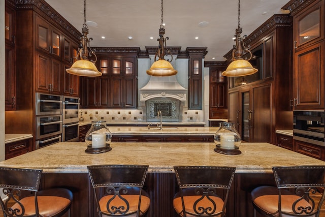 kitchen featuring a breakfast bar area, decorative light fixtures, and a large island with sink