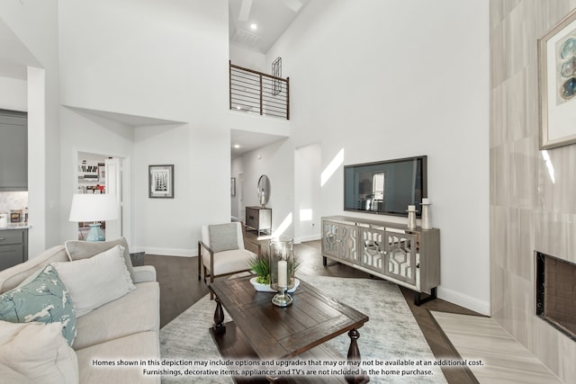 living room featuring hardwood / wood-style flooring, a tiled fireplace, and a towering ceiling