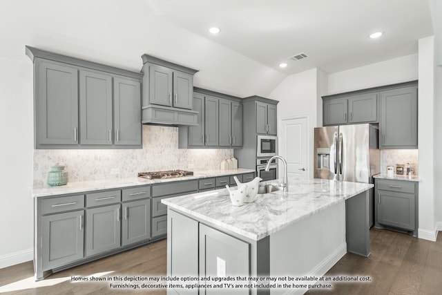 kitchen featuring gray cabinetry, dark wood-type flooring, a kitchen island with sink, and stainless steel appliances