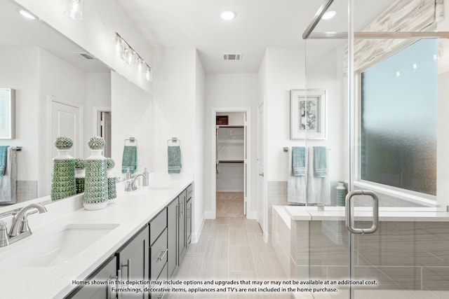 bathroom with tile patterned floors, a wealth of natural light, tiled tub, and vanity