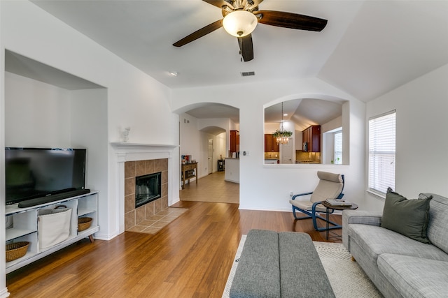 living room with a fireplace, ceiling fan with notable chandelier, hardwood / wood-style floors, and vaulted ceiling