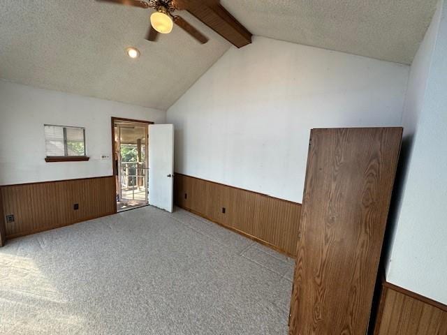 empty room featuring lofted ceiling, ceiling fan, light colored carpet, and a textured ceiling