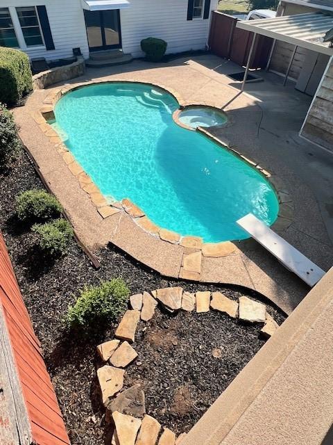 view of swimming pool with a diving board and a patio