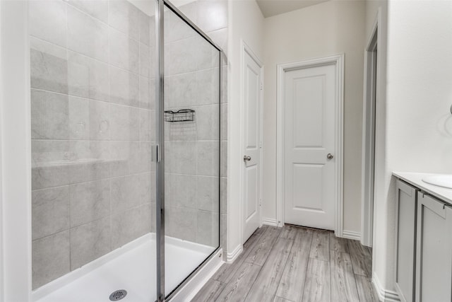 bathroom with vanity, hardwood / wood-style floors, and a shower with door