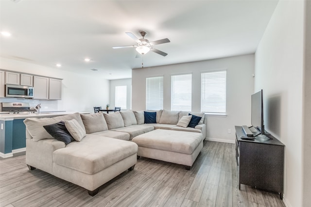 living room featuring ceiling fan and light hardwood / wood-style flooring