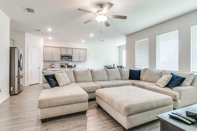 living room featuring ceiling fan and light hardwood / wood-style floors