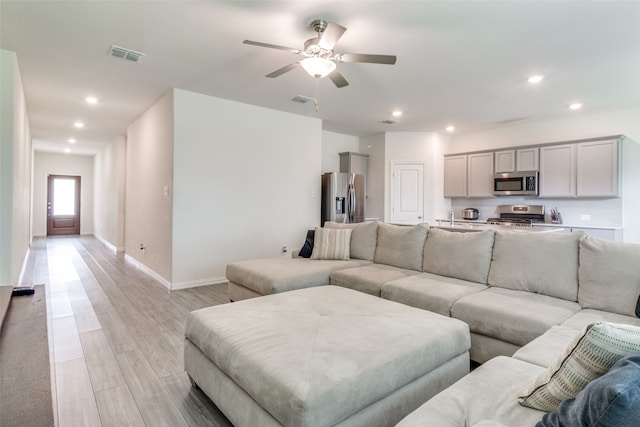 living room with light hardwood / wood-style flooring and ceiling fan