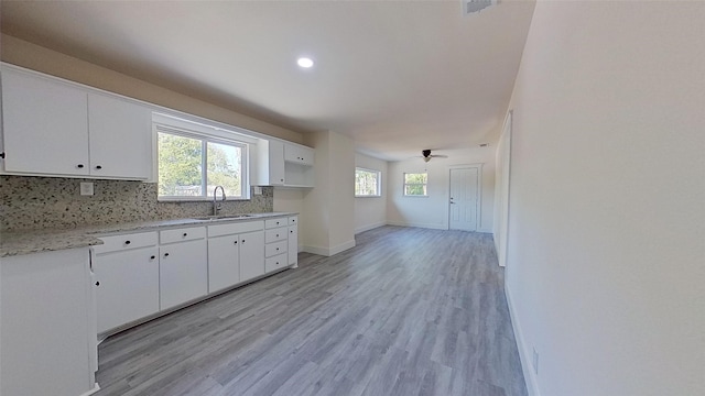 kitchen with tasteful backsplash, light hardwood / wood-style floors, white cabinets, and ceiling fan