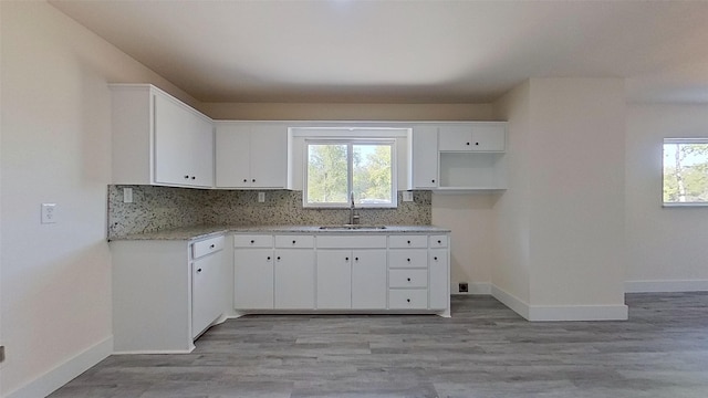 kitchen with white cabinets, light hardwood / wood-style flooring, plenty of natural light, and sink