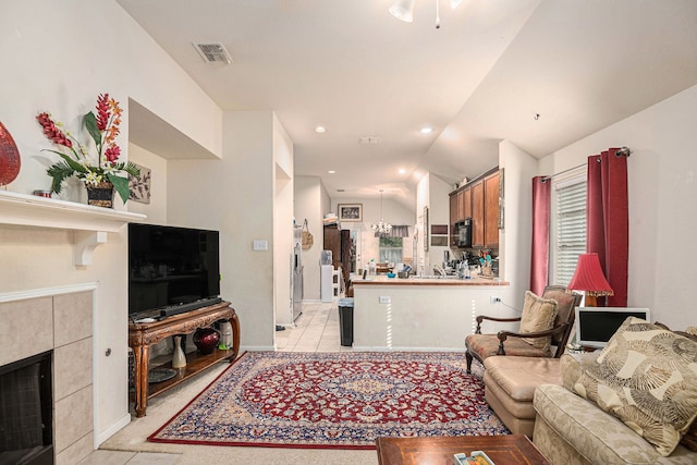 living room with lofted ceiling, a tiled fireplace, and light tile patterned floors