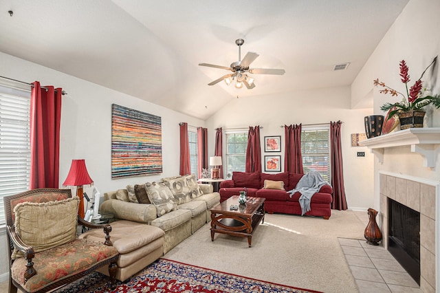 living room featuring lofted ceiling, light colored carpet, a tile fireplace, and ceiling fan