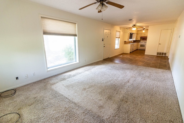 unfurnished living room with ceiling fan and dark carpet