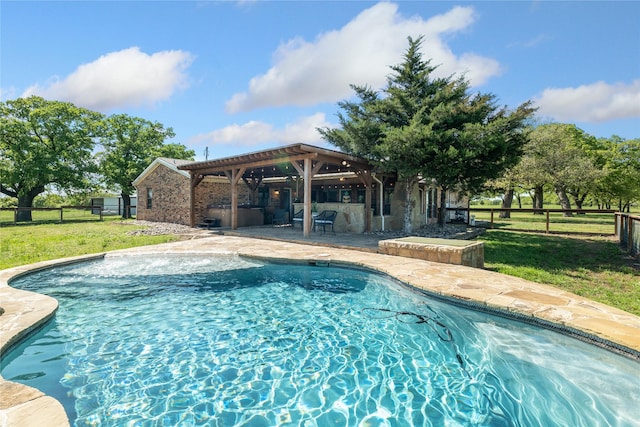 view of swimming pool featuring a lawn, a patio area, and exterior kitchen