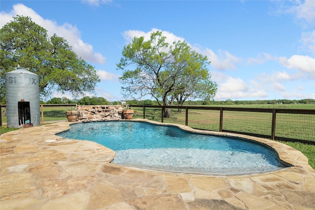 view of swimming pool featuring a fenced in pool, a patio area, fence, and a rural view