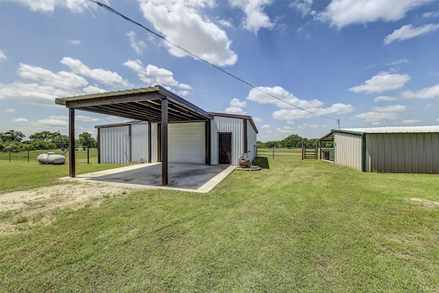 view of yard featuring a garage, a carport, and an outdoor structure