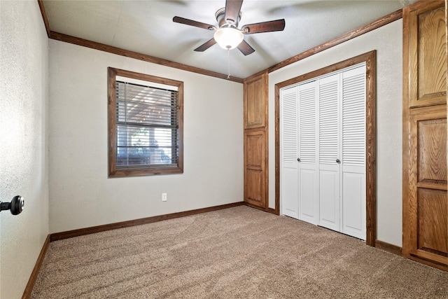 unfurnished bedroom featuring carpet flooring, a closet, ceiling fan, and crown molding