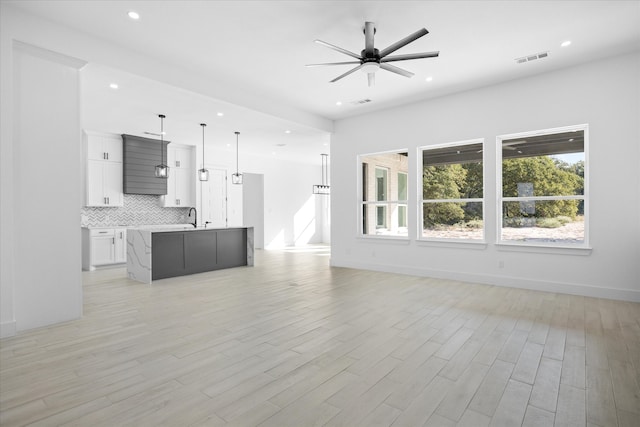 unfurnished living room with ceiling fan, light hardwood / wood-style flooring, and sink