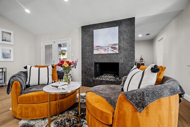 living room with hardwood / wood-style flooring, lofted ceiling, and a tile fireplace