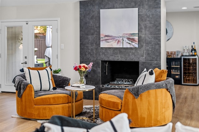 living room with a fireplace, beverage cooler, hardwood / wood-style flooring, and tile walls