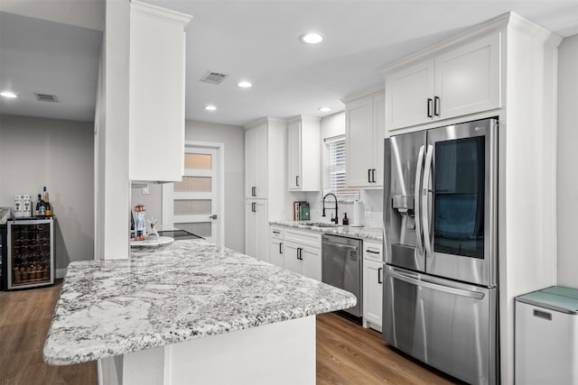 kitchen featuring dark hardwood / wood-style flooring, wine cooler, sink, stainless steel appliances, and white cabinetry