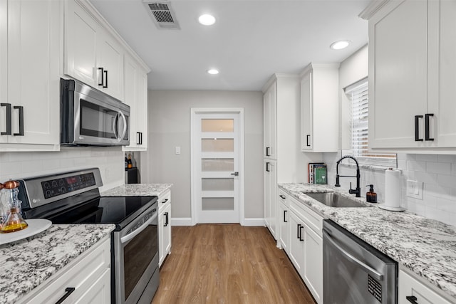 kitchen featuring appliances with stainless steel finishes, light hardwood / wood-style flooring, sink, and white cabinets