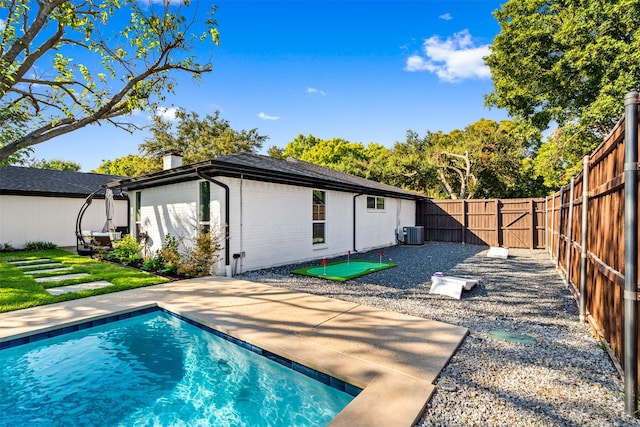 rear view of house with central AC unit, a fenced in pool, and a patio area