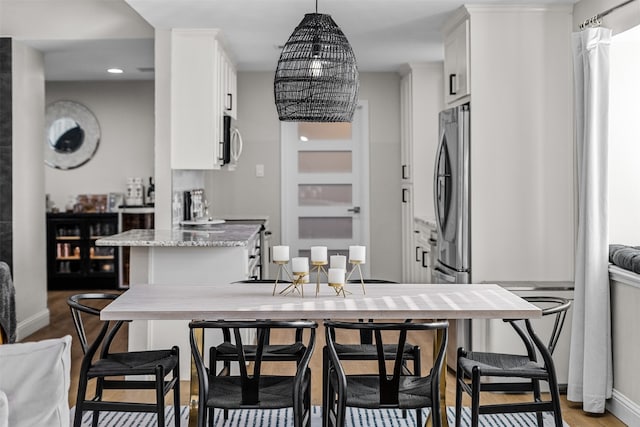 kitchen featuring stove, light hardwood / wood-style flooring, light stone counters, a kitchen bar, and white cabinetry