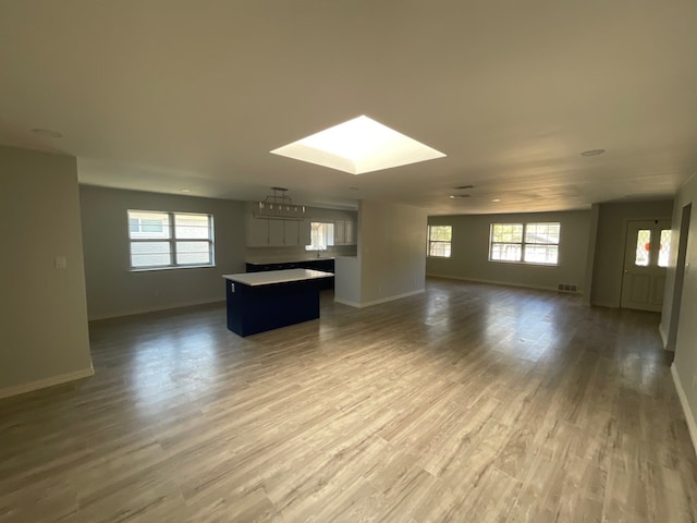 unfurnished living room with a skylight and hardwood / wood-style flooring