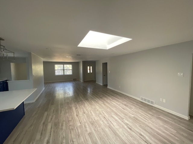 unfurnished living room featuring a skylight and hardwood / wood-style flooring