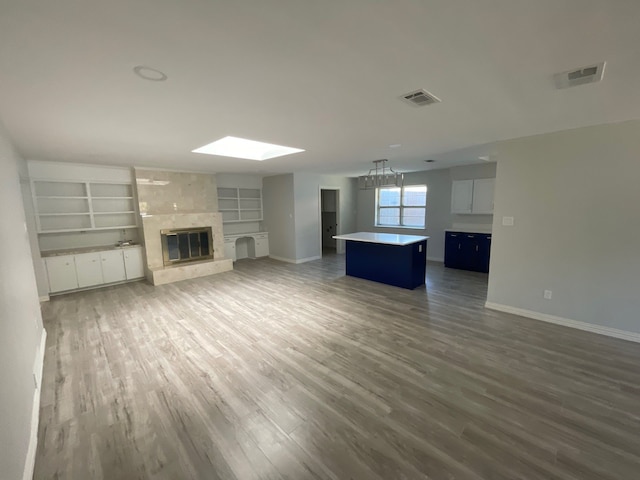 unfurnished living room featuring dark wood-type flooring, a large fireplace, and built in shelves