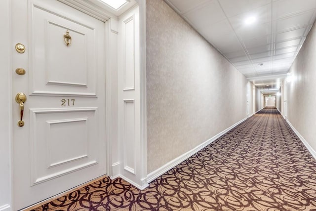 hall featuring baseboards and carpet floors