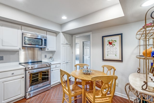 kitchen with stainless steel appliances, dark parquet floors, and white cabinetry