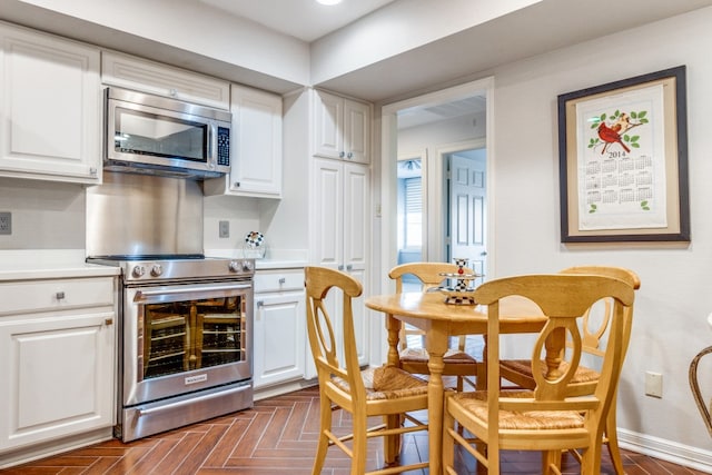 kitchen with appliances with stainless steel finishes, dark parquet flooring, and white cabinets