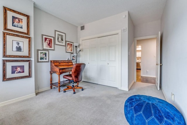 office space featuring a textured ceiling, carpet floors, visible vents, and baseboards