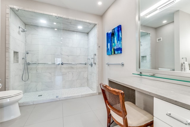 bathroom featuring vanity, tile patterned flooring, toilet, and tiled shower